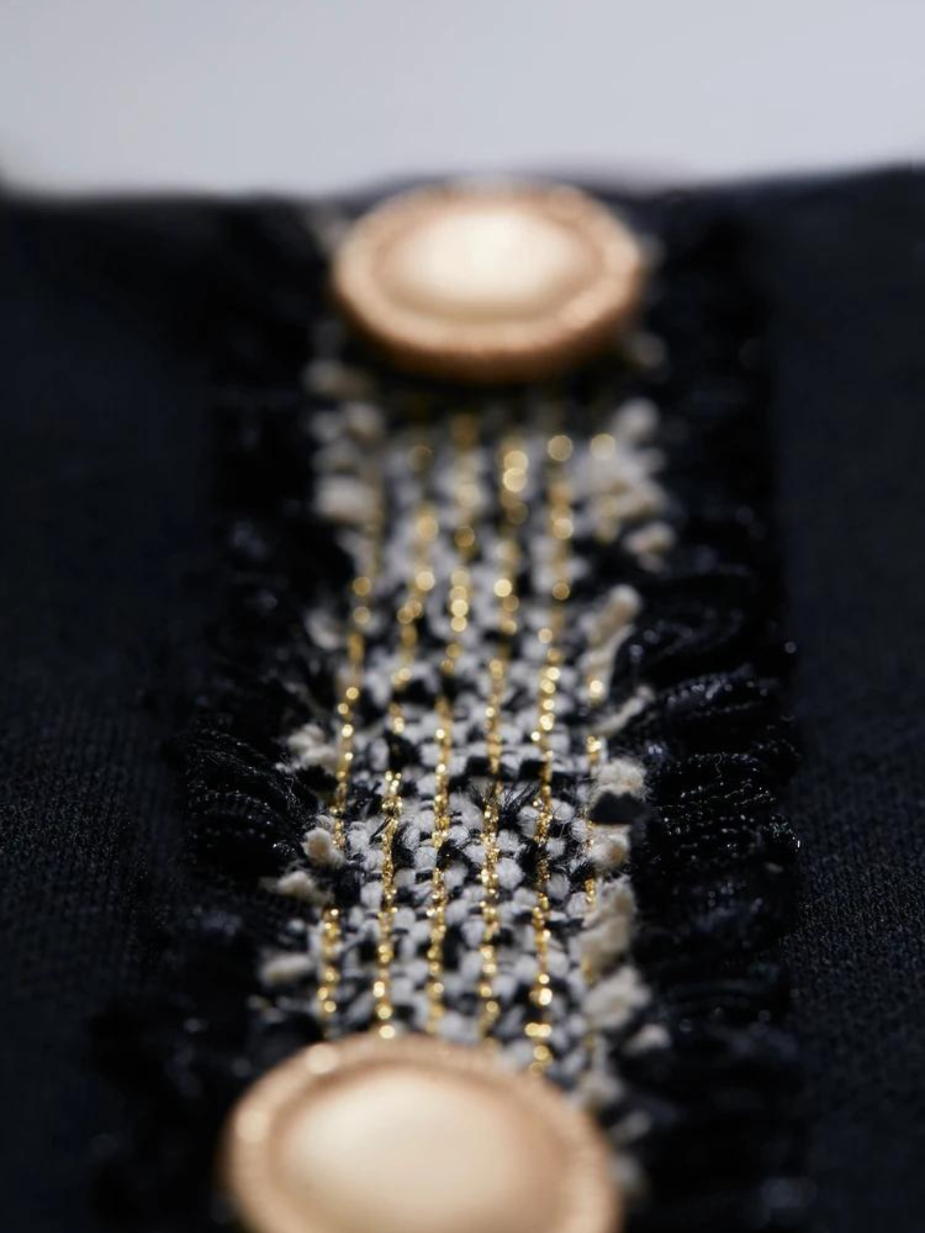 A close up of the gold button details of a black dress.