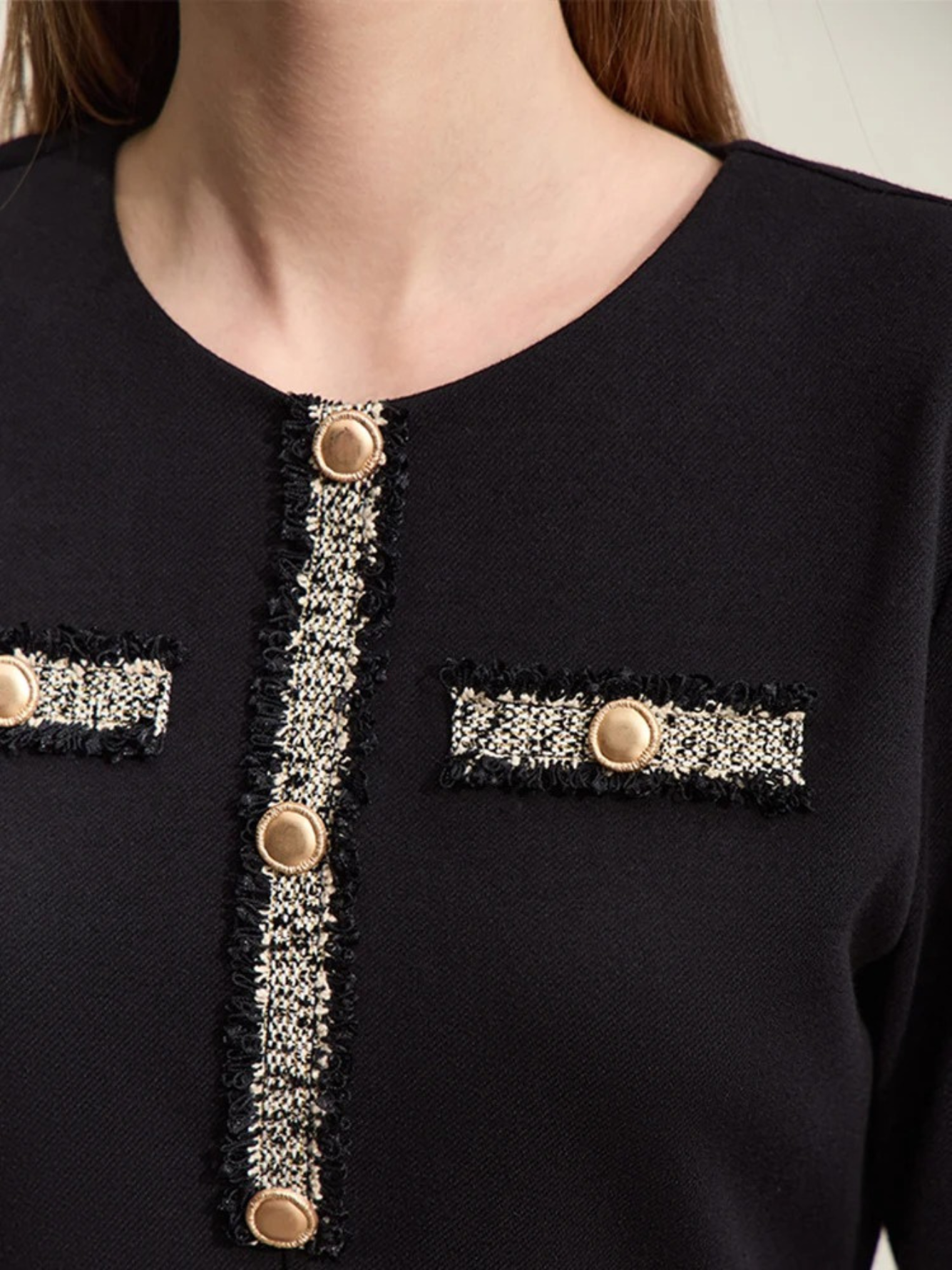 The embroidery and gold buttons detailing on a black dress.