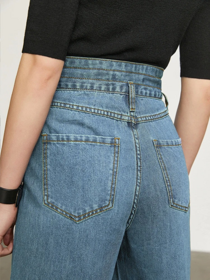 A close up of the waist and back pocket details of a high waisted pair of denim jeans.