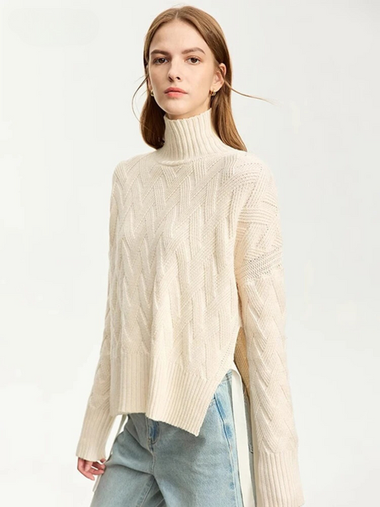 A woman wearing a cream colored turtleneck sweater with a ribbed design on the neckline and wrists and a chevron knit pattern with a tie design on both sides.